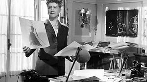 Assistenin Solange, die als starke Frau den Laden im Kern zusammenhält, begutachtet die Entwürfe ihres Chefs. © Arthaus / Studiocanal